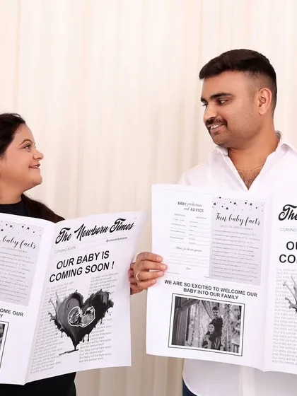 A fun and creative pregnancy announcement photo with the couple holding custom newspapers in our studio.