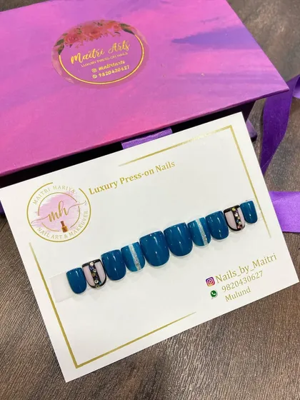 A bold and beautiful press-on set in a deep teal color, with striped and jeweled accent nails.