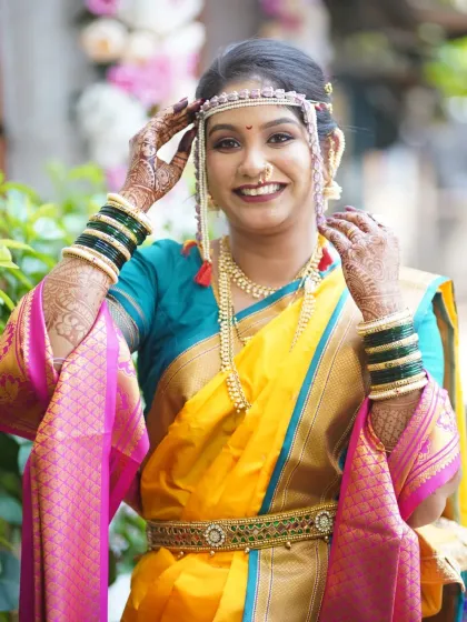 A joyful pose from the bride, showing off her full attire. The yellow Nauvari, green bangles, and radiant makeup create a picture-perfect look.