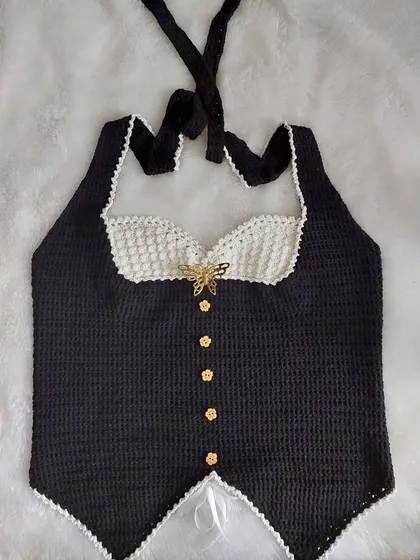 A flat-lay of the Belladonna Top, showing the full design with its halter straps, corset-style body, and delicate scalloped edging.