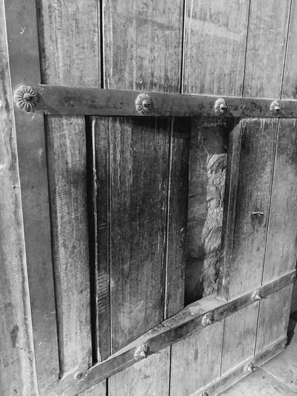 A close-up of an old wooden door with traditional iron fittings. We focus on the craftsmanship and architectural details that have survived for centuries in Old Delhi.