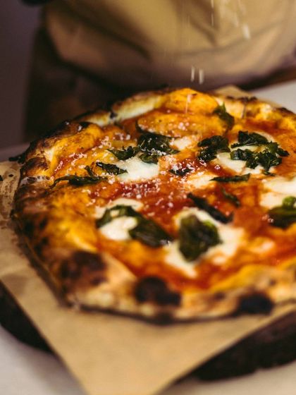 Pizza lovers, rejoice. Your favourite pies are waiting. A final dusting of parmesan cheese completes this beautiful Margherita pizza.