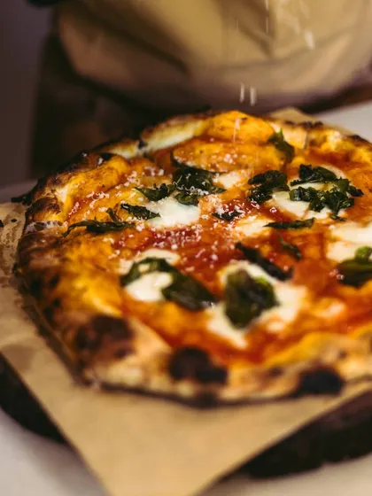 A final sprinkle of Parmesan cheese adds that extra touch of savory flavor to a freshly baked pizza before it heads to your table.