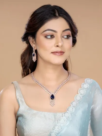 This shot features a model wearing a delicate diamond necklace with a deep blue gemstone. The soft lighting and elegant saree pairing make it ideal for showcasing fine jewellery for evening wear.