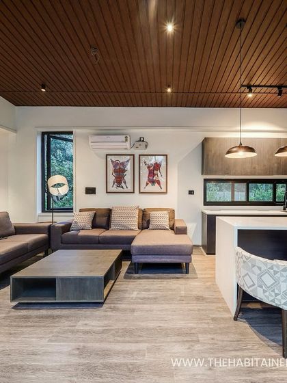 The spacious living and dining area of a container home, featuring a wood-paneled ceiling and modern furniture.
