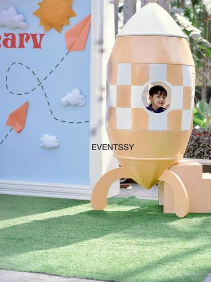 The birthday boy peeking out of the window of his very own rocket ship prop, creating a fun and interactive photo moment.