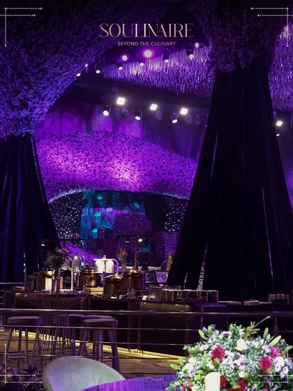 The stunning, immersive decor at a social affair at Nevaeh, with large, purple floral structures creating a fantasy-like atmosphere. We cater in environments that are as spectacular as our food.