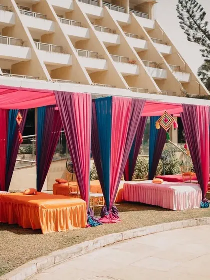 Colorful draped cabanas for a Mehendi function. These provide comfortable and stylish seating for guests, with vibrant colors that match the festive mood of the event.