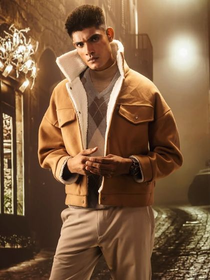 A moody, cobblestone alley at night, created with projection. The lighting is dramatic and focused, highlighting the model's powerful stance and the texture of his jacket.