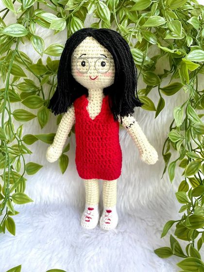 A thoughtful farewell gift for a niece heading off to higher studies. This replica doll in a red dress stands with her pet cat on a display base, a reminder of home she can take with her.