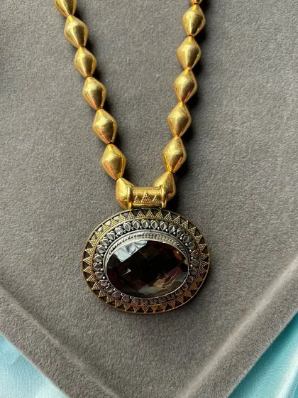 A premium pure silver necklace with a gold-plated finish. This piece features a large, oval smoky quartz stone set in a dual-tone frame, combining modern design with classic materials.