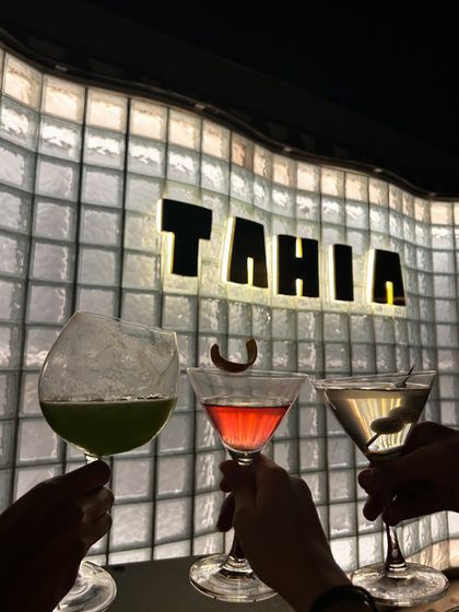 A cheers-ing shot with colorful cocktails at Tahia. This is a classic and engaging way to showcase a restaurant's drink menu.