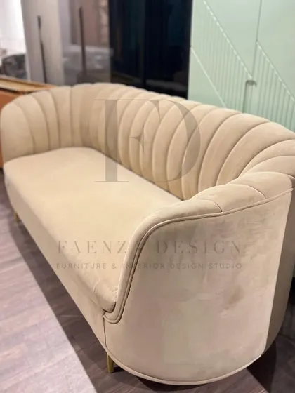 This sofa features a beautiful scalloped, channel-tufted back in a soft beige fabric. The elegant curves and brass-finished legs give it a touch of Art Deco-inspired glamour.