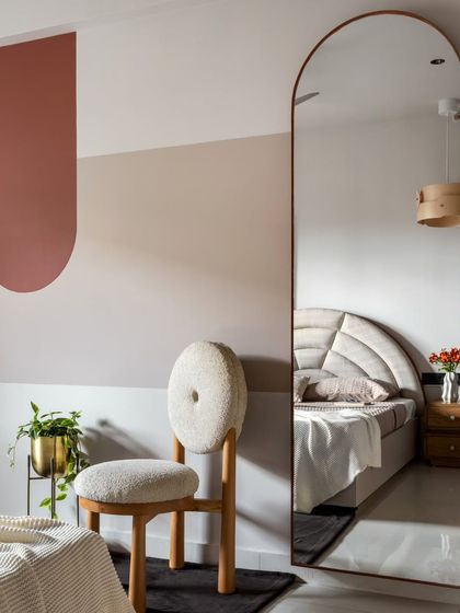 Simple color blocking and a full-length arched mirror create visual play in the guest bedroom without adding clutter. The reflection makes the room feel larger and brighter.