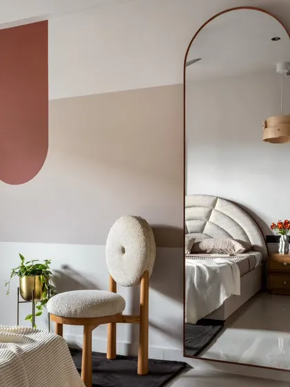 Simple color blocking and a full-length arched mirror create visual play in the guest bedroom without adding clutter. The reflection makes the room feel larger and brighter.