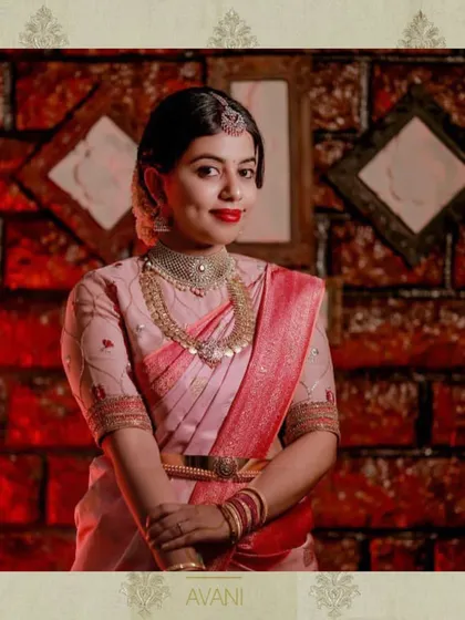 A bride in a pink Kanchipuram saree. Her custom blouse features delicate floral embroidery, adding a soft and romantic touch to her look.
