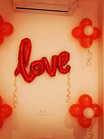 Creating a romantic surprise. A simple 'LOVE' foil balloon surrounded by red balloon flowers is a sweet gesture for an anniversary or Valentine's Day.