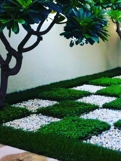 My work isn't just for walls. I design unique groundscapes like this checkerboard pattern using squares of artificial grass and white pebbles, perfect for patios, gardens, and walkways.
