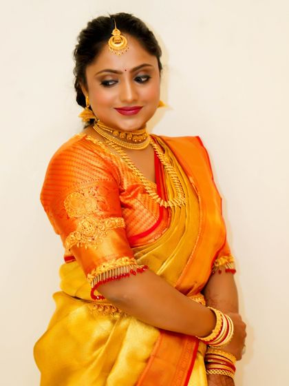 A close-up of the bride's happy expression. The makeup is warm and inviting, with a soft smokey eye and a lip color that complements the saree.