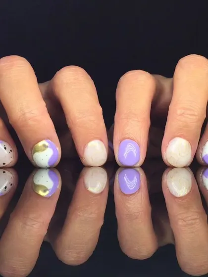 A playful abstract design with purple and white polish, accented with gold foil and black dots.