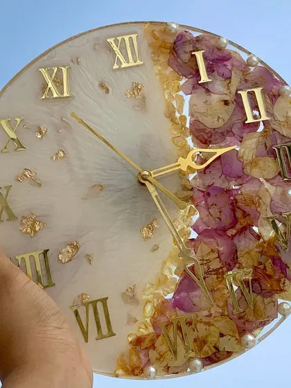 A varmala preservation clock held in hand, showing the beautiful combination of preserved flowers and a functional timepiece.