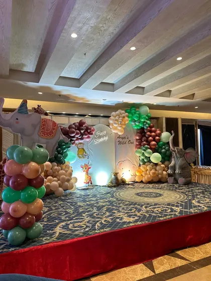 A 'Wild One' jungle theme is one of our favorite setups for a child's first birthday. This party featured a full stage with balloon arrangements in earthy tones, cute animal props like elephants and giraffes, and a custom backdrop for a fun-filled adventure.