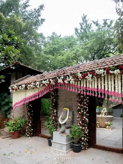 The entrance gates adorned with garlands of white and red flowers, creating a festive welcome.