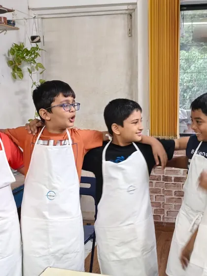 The best part of a pottery party is the fun you have with your friends. These boys are sharing a laugh after their creative session, proudly wearing their aprons.