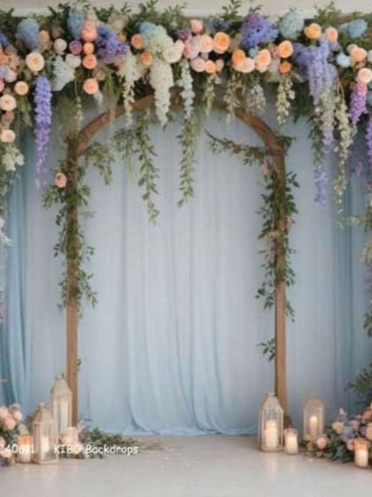 This is an example of a simple and elegant floral archway. The design uses pastel flowers and hanging greenery over a wooden frame, perfect for a photo booth or entrance decor.
