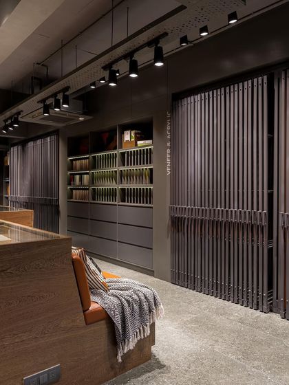 The dark, moody color scheme of the showroom allows the natural warmth and texture of the wood veneers to take center stage.