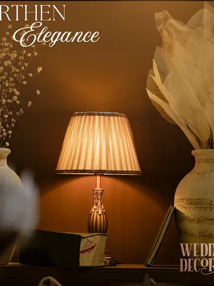 A composition of rustic vases, dried florals, and a softly lit lamp, embodying the 'Earthen Elegance' theme.