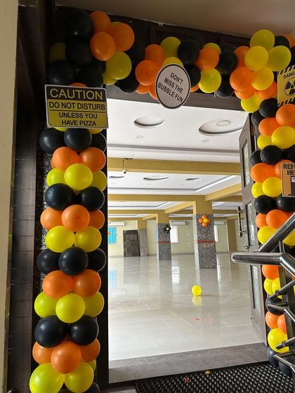 An entrance arch for a construction party with fun, custom signs. The black, yellow, and orange balloons match the theme perfectly.