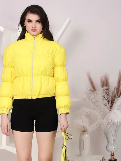 A bright yellow puffer jacket modeled against a stylized white studio background, making the product color pop.