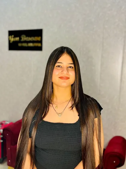 A front view of the client with long, sleek hair and caramel highlights. The color placement is designed to enhance her features and the length of her hair.