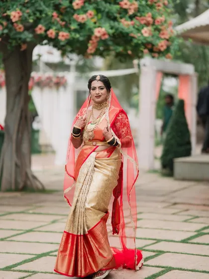 The bride makes her entrance, her red veil adding a touch of drama and tradition. Her makeup remains flawless and radiant, ready for the main ceremony.
