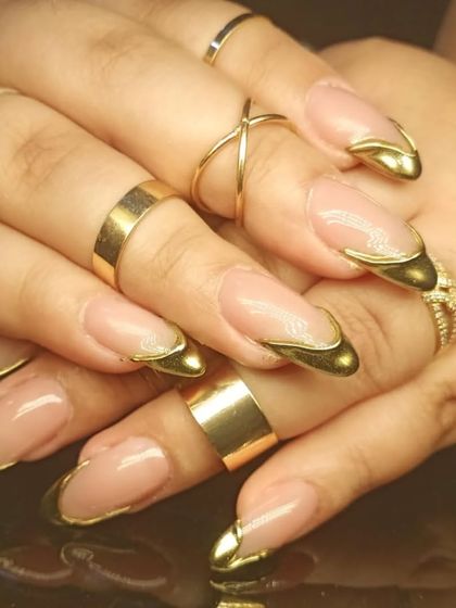 A side view of the sculpted gold chrome French tips, showing the dimension and high-shine finish.