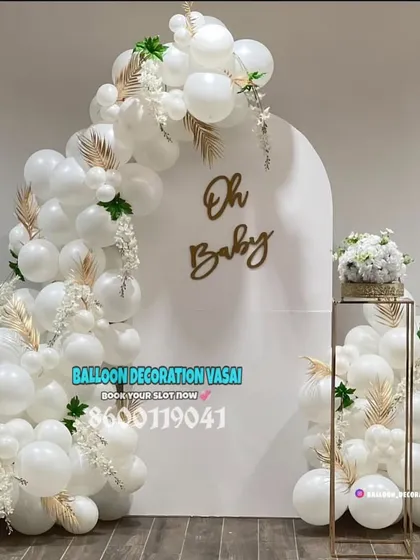 This minimalist "Oh Baby" setup shows how simple can be stunning. The all-white balloon arch, accented with gold leaves and a chic backdrop, brings a touch of modern elegance to any baby shower, perfect for intimate home celebrations.