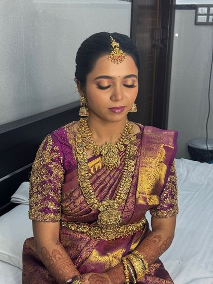 A moment of calm before the ceremony. This shot showcases the full effect of the bridal jewellery, from the nethichutti on her forehead to the layered necklaces and matching jhumkas.