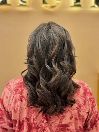 The back of a medium-length haircut with subtle highlights and soft waves, showcasing a creative and stylish look.