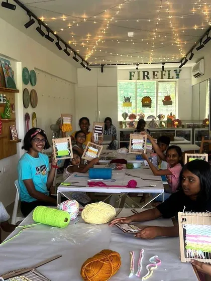 A full classroom of happy campers holding up their finished weaving projects. The room is buzzing with creative energy and pride. I love these moments!