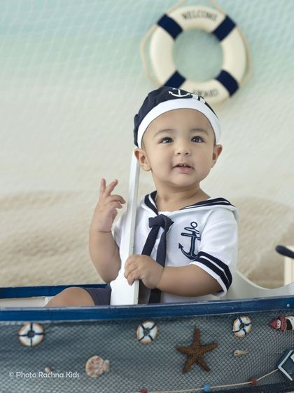 A sweet, curious expression from our little sailor, holding his oar and ready for adventure.