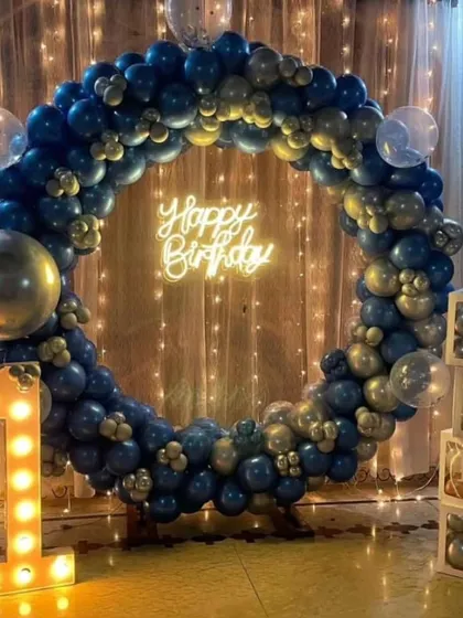 A first birthday celebration with a blue and gold theme. The balloon ring, lighted number "1", and "BABY" blocks create a complete and stylish photo corner.
