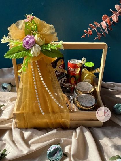 A special confectionery wedding hamper, perfect for gifting. This pinewood basket is elegantly wrapped and filled with a variety of snacks, cookies, and drinks.