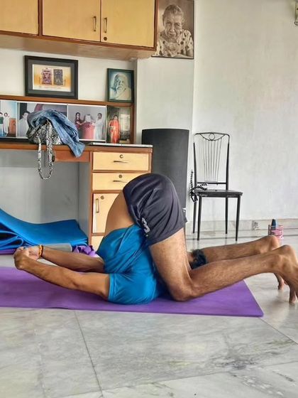 A student practices Karnapidasana (Ear Pressure Pose). This deep forward bend is part of our intermediate and advanced sequences, helping to calm the nervous system and stretch the entire spine.