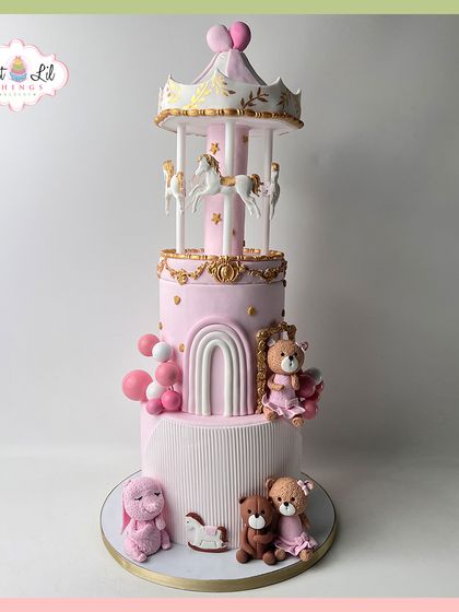 A fairytale carousel cake that is pure magic. This grand, multi-tiered pink and gold cake is topped with a working carousel and surrounded by adorable teddy bears.