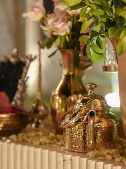 A wider shot of the console table, showing how the collection of vintage brass items, florals, and candles comes together to create an elegant and welcoming display.