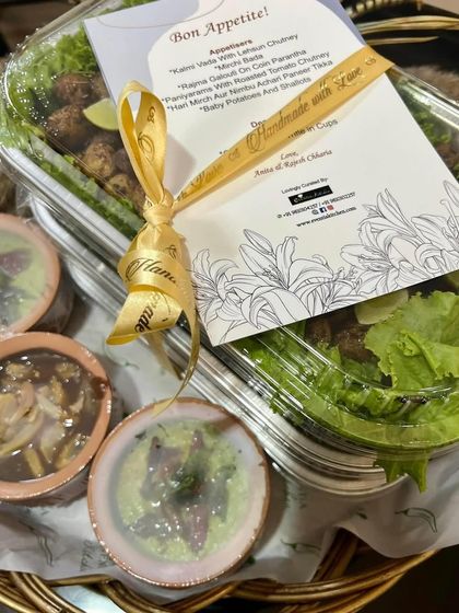 This platter showcases a variety of appetizers and dips, including Kalmi Vada and Rajma Galouti. The menu card tied with a ribbon details the entire spread, making it a perfect gift or a treat for your own family.