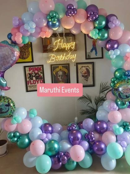 A different take on the mermaid theme, with a circular balloon arch in pastel shades of purple, pink, and mint green. A mermaid tail balloon and a neon sign complete the look.