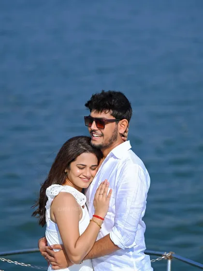 A sun-filled, candid portrait of a couple embracing on the deck of a boat. This pre-wedding photo captures a moment of pure happiness against the sparkling water.