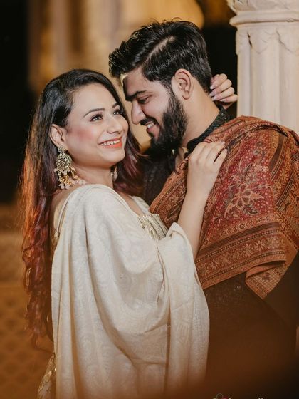 A happy, candid moment between the couple. The makeup is natural and radiant, highlighting her smile and the joy of the moment.